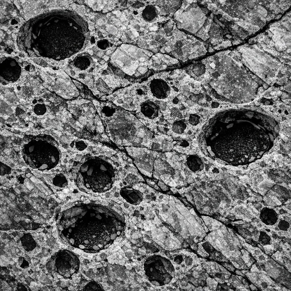 Microscopic view of 'Stone Porosity'. shows the natural fissures and mineral pores in a granite surface where liquids can be trapped and cause deep stains. Scientific monochrome aesthetic, sharp detail, 8k resolution.